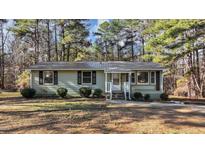 Charming single-story home with a metal roof, nestled among mature trees and well-manicured landscaping at 749 Fred Royster Rd, Henderson, NC 27537