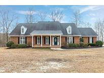 Charming brick home features a well-manicured lawn and welcoming front porch with columns at 8724 Ten Ten Rd, Raleigh, NC 27603