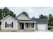 Charming single-story home featuring light siding, black shutters, and a well-maintained front yard at 104 Ginger Cir, Selma, NC 27576