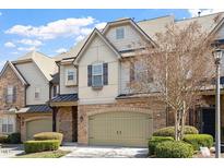 Charming townhome featuring a two-car garage, stone accents, and well-maintained landscaping at 105 Sunstone Dr, Cary, NC 27519