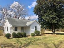 Charming single-Gathering home with white siding and mature landscaping on a sunny day at 1111 Spring Valley Lake Rd, Henderson, NC 27537