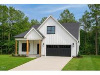 New home with a modern farmhouse design, black garage door, a manicured lawn, and black trim windows at 148 Mohawk Dr, Louisburg, NC 27549