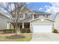Two-story home featuring solar panels, a two-car garage, manicured landscaping, and a welcoming front porch at 16 Juliette Drive, Durham, NC 27713