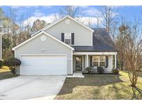 Charming two-story home with a well-manicured lawn, attached garage, and a cozy front porch sitting area at 201 Timber Meadow Lk, Fuquay Varina, NC 27526