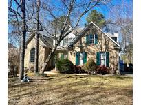 Charming brick home with green shutters and mature trees in a well-maintained yard at 300 Barthel Dr, Cary, NC 27513