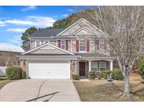 Charming two-story home with a stone and siding facade, red shutters, a well-manicured lawn, and an attached two-car garage at 3100 Cynthiana Ct, Raleigh, NC 27610