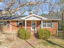 Charming brick home featuring a covered front porch, walkway, and mature landscaping at 407 Knight Ave, Cary, NC 27511
