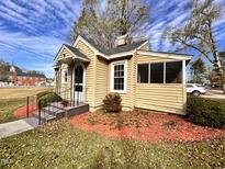 Charming yellow home with a landscaped yard, a screened-in porch and a black metal handrail at 415 Caswell St, Smithfield, NC 27577
