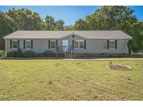 Charming single-story home with a well-manicured lawn, complemented by mature trees and an American flag at 7850 Nc 42, Holly Springs, NC 27540