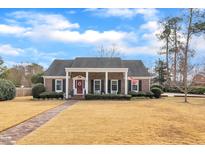 Charming brick home featuring a columned front porch, red door, and well-maintained landscaping at 811 S First St, Smithfield, NC 27577