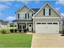 Charming two-story home features a manicured lawn, covered porch, and a two-car garage at 897 W Main St, Benson, NC 27504