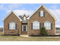 Charming brick home featuring arched windows, black shutters, dormer window, and a manicured front yard at 124 D'Ango Cir, Angier, NC 27501