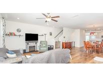 Bright living room featuring a fireplace, ceiling fan, and open access to the dining area and staircase at 234 Palmetto Tree Way, Knightdale, NC 27545