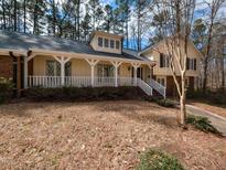 Charming yellow home with a welcoming porch, white railings, and mature trees at 241 Beachers Brook Ln, Cary, NC 27511
