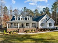 Stunning two-story home boasting a welcoming front porch, beautiful landscaping, and a classic white facade at 290 Whistlers Cv, Louisburg, NC 27549