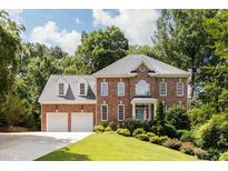 Beautiful two-story brick home with a well-manicured lawn and a two-car garage, surrounded by lush greenery and trees at 3359 Hampton Rd, Raleigh, NC 27607