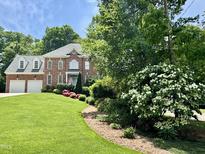 Beautiful brick home featuring a manicured lawn, mature trees, and flowering shrubs at 3359 Hampton Rd, Raleigh, NC 27607