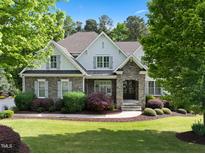 Charming two-story home featuring stone accents, lush landscaping, and a well-manicured lawn at 6829 Palaver Ln, Cary, NC 27519