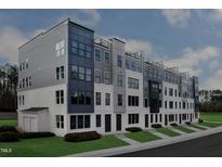 Modern townhome exterior with gray and white facade, lush landscaping, and sidewalk at 10531 Pleasant Branch Dr # 201, Raleigh, NC 27614