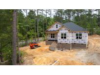 New construction home with brick foundation, black roof, and protective wrap against wooded backdrop at 15 Bourbon St, Fuquay Varina, NC 27526