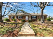 Charming brick home featuring a classic design, manicured lawn, and inviting front porch at 2103 Huntington Rd, Burlington, NC 27215
