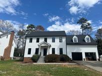 Charming two-story home featuring a clean white facade, dark trim, and inviting front entrance with a well manicured lawn at 2112 Hamrick Dr, Raleigh, NC 27615
