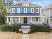 Charming blue two-story home featuring a welcoming front porch with white railings and beautiful landscaping at 2118 Cloud Cover Ln, Raleigh, NC 27614