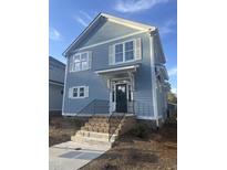 Charming two-story home featuring light blue siding, white trim, and a welcoming front entrance with brick steps at 2218 Woodrow St, Durham, NC 27705