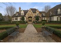 Elegant stone and brick home with mature landscaping, a brick walkway, and inviting benches at 266 Perfect Moment Dr, Durham, NC 27713
