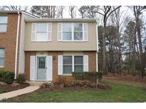 Charming townhouse with brick and beige siding, complemented by white window shutters and a well-maintained lawn at 7746 Kingsberry Ct, Raleigh, NC 27615