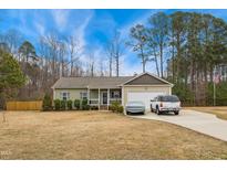 Charming single-story home with a well-manicured lawn and attached garage, and vehicles parked in the driveway at 10923 Selma Rd, Middlesex, NC 27557