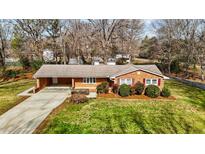 Charming brick home featuring a well-maintained lawn and mature landscaping, creating a welcoming curb appeal at 1837 Shamrock Dr, Burlington, NC 27215