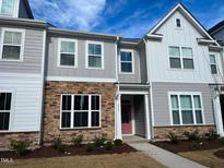 Charming townhome with stone accents, a light pink door, and manicured landscaping at 2335 Whitewing Ln, Wendell, NC 27591