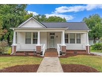 Charming home with a welcoming front porch, white siding, and a beautifully landscaped yard at 308 Charles St, Henderson, NC 27536