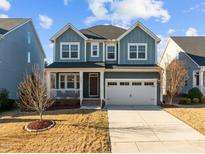 Charming two-story home with a covered porch and a two-car garage on a sunny day at 5121 Windmere Chase Dr, Raleigh, NC 27616