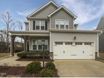 Charming two-story home with gray siding, a front porch, and a two-car garage with white doors at 79 E Copenhaver Dr, Clayton, NC 27527