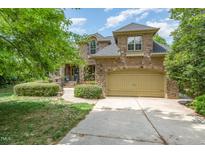 Brick home featuring an attached garage and well maintained landscaping on a sunny day at 101 Tussled Ivy Way, Cary, NC 27513