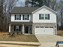 Two-story home featuring stone accents, a two-car garage, black shutters, and a well-manicured lawn at 104 Wilderness Ct, Mebane, NC 27302