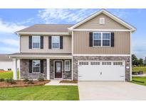 Two story home with stone accents, neutral siding, two car garage and a well manicured lawn at 104 Wilderness Ct, Mebane, NC 27302