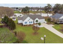 Beautiful lakefront home featuring white siding, blue shutters, mature landscaping, and a long driveway at 123 Glasgow Dr, Clayton, NC 27520