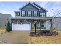 Charming two-story home with stone accents, a white garage door, and a well-maintained lawn at 157 W Copenhaver Dr, Clayton, NC 27527