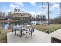 Enjoy this lovely lake view from the outdoor patio featuring a patio table and chairs set under a large umbrella at 2118 Timberlake Dr, Raleigh, NC 27604