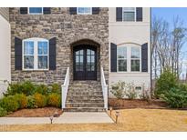 Elegant stone and brick home with a welcoming arched entryway and manicured landscaping at 329 Royal Delta Dr, Cary, NC 27519