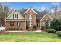 Charming brick home featuring a manicured lawn, mature trees, and a welcoming entrance at 7001 Millstone Ridge Ct, Raleigh, NC 27614