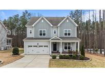 Charming two-story home featuring a covered front porch, attached garage, and well-maintained landscaping at 8816 Knights Union Way, Wake Forest, NC 27587