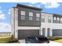 Modern two-story townhome showcasing a dark garage door and a mix of white brick and gray siding at 1004 Westerland Way # 197, Durham, NC 27703