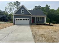 Charming single-Gathering home boasts a well-manicured lawn, attached two-car garage and welcoming red front door at 162 Kirkwall Ln, Selma, NC 27576