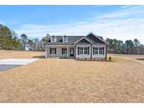 Charming new construction home featuring a manicured lawn, black shutters, and light gray siding at 3131 Pilson Rd, Cameron, NC 28326