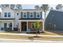 Charming two-story home featuring a brick facade, gray shingles, and a well-manicured lawn at 3719 Rosebush Dr, Zebulon, NC 27597