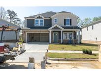 Two-story home with an open garage, a well-manicured lawn, and a contemporary design at 3829 Rosebush Dr, Zebulon, NC 27597